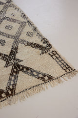 Remi is a vintage Beni Ourain from the middle Atlas mountains, with a rare design featuring tribal symbology. Thick natural wool carpet in black and white pattern.
