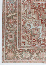 A handwoven 100‑year‑old Persian rug from NW Iran with a typical Heriz design and a rust and olive colour palette.