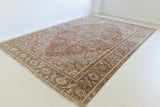 An antique Persian carpet featuring a Heriz design and a rich rust colour palette.