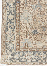 The Portia rug features an intricate all over Heriz design comprised of floral and palmette motifs set against a taupe ground and muted blue toned boarder. A beautiful antique carpet.