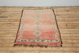 A vintage Boujad rug with a peach and sage green color palette, featuring geometric patterns and berber symbology, approximately 40 years old