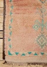 A vintage Boujad rug with a peach and sage green color palette, featuring geometric patterns and berber symbology, approximately 40 years old