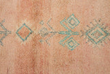 A vintage Boujad rug with a peach and sage green color palette, featuring geometric patterns and berber symbology, approximately 40 years old