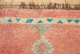 A vintage Boujad rug with a peach and sage green color palette, featuring geometric patterns and berber symbology, approximately 40 years old