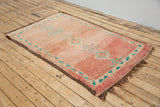 A vintage Boujad rug with a peach and sage green color palette, featuring geometric patterns and berber symbology, approximately 40 years old