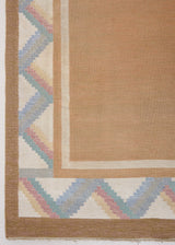 A Swedish geometric-patterned rug with multicolor border on a beige background. This röllakan rug was handwoven by the mid-century textile designer Anna Johanna Angström.