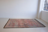 Beni M’guild thick piled carpet. Rug features a dark blue geometric pattern on a peachy pink background.