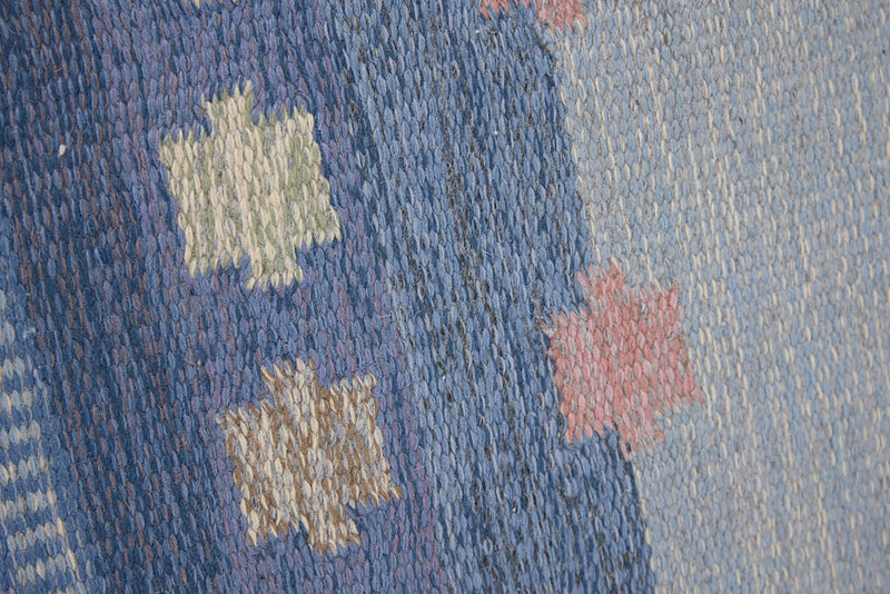 an original Swedish röllakan rug handwoven by mid-century textile designer Anna Johanna Angström. Her colourful kilim features strong lines in a blue and pale blue checkered pattern with accents of pink and cream