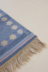 an original Swedish röllakan rug handwoven by mid-century textile designer Anna Johanna Angström. Her colourful kilim features strong lines in a blue and pale blue checkered pattern with accents of pink and cream