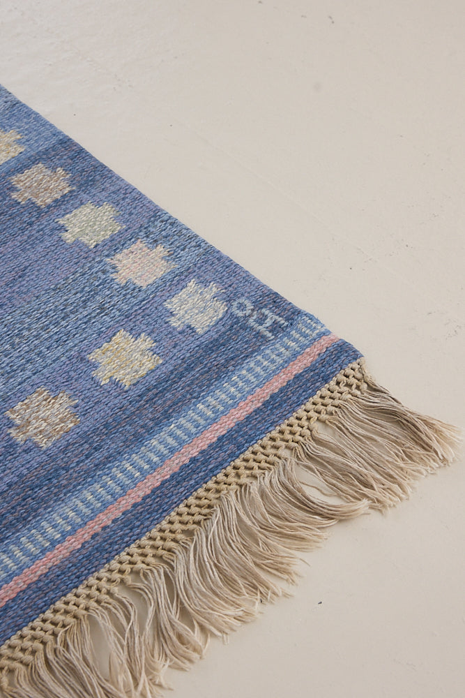 an original Swedish röllakan rug handwoven by mid-century textile designer Anna Johanna Angström. Her colourful kilim features strong lines in a blue and pale blue checkered pattern with accents of pink and cream