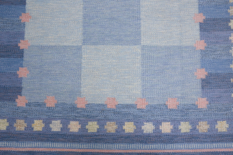 an original Swedish röllakan rug handwoven by mid-century textile designer Anna Johanna Angström. Her colourful kilim features strong lines in a blue and pale blue checkered pattern with accents of pink and cream