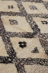 Remi is a vintage Beni Ourain from the middle Atlas mountains, with a rare design featuring tribal symbology. Thick natural wool carpet in black and white pattern.