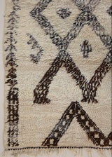 Remi is a vintage Beni Ourain from the middle Atlas mountains, with a rare design featuring tribal symbology. Thick natural wool carpet in black and white pattern.