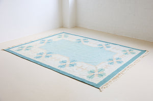 Elio is a pretty blue Swedish flatweave, featuring a bold geometric floral design with hints of beige and pink within the motifs.