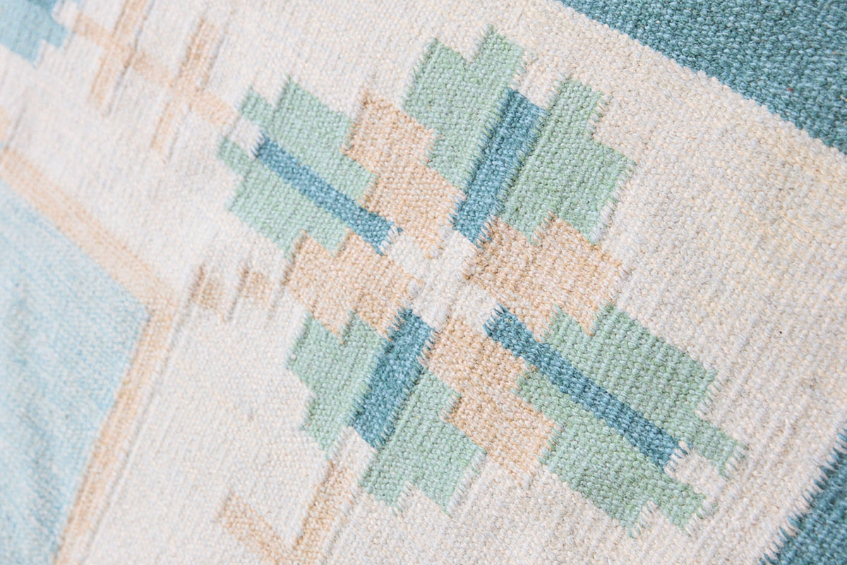 Elio is a pretty blue Swedish flatweave, featuring a bold geometric floral design with hints of beige and pink within the motifs.