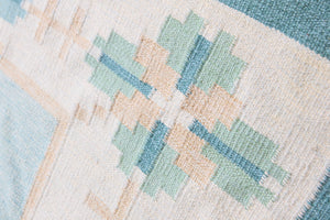 Elio is a pretty blue Swedish flatweave, featuring a bold geometric floral design with hints of beige and pink within the motifs.