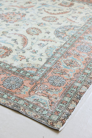 Genevieve is a vintage Turkish Oushak rug. Oushaks are defined by their softness in palette and large-scale, open compositions.The muted beige field is decorated with pretty floral scrolls, framed by a soft pinky red border.