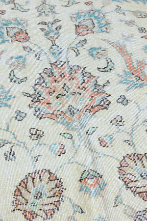 Genevieve is a vintage Turkish Oushak rug. Oushaks are defined by their softness in palette and large-scale, open compositions.The muted beige field is decorated with pretty floral scrolls, framed by a soft pinky red border.