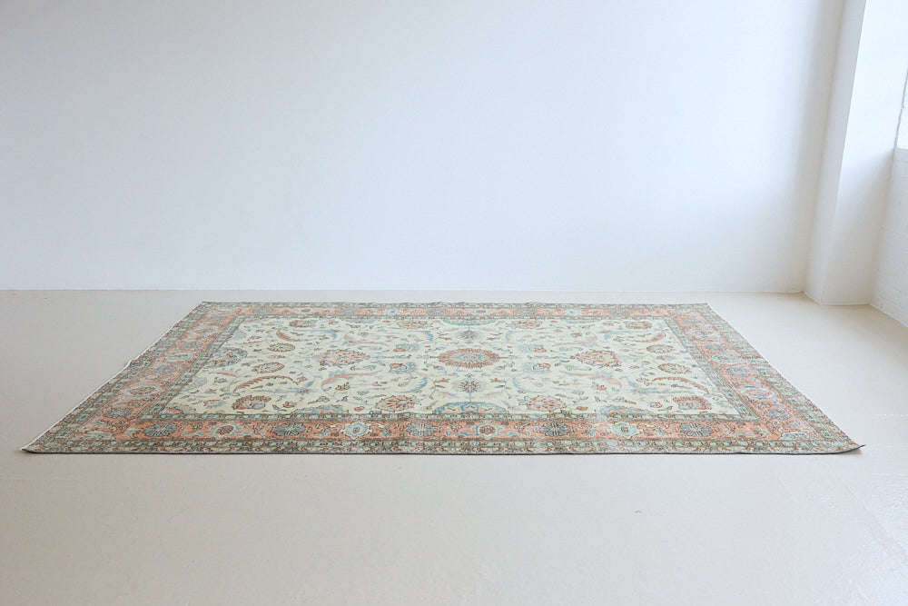 Genevieve is a vintage Turkish Oushak rug. Oushaks are defined by their softness in palette and large-scale, open compositions.The muted beige field is decorated with pretty floral scrolls, framed by a soft pinky red border.