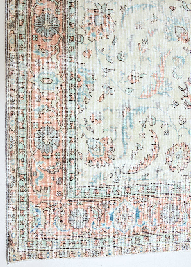 Genevieve is a vintage Turkish Oushak rug. Oushaks are defined by their softness in palette and large-scale, open compositions.The muted beige field is decorated with pretty floral scrolls, framed by a soft pinky red border.