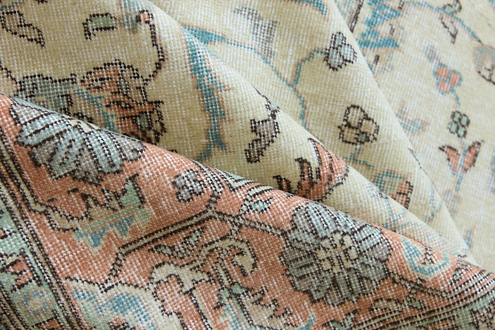 Genevieve is a vintage Turkish Oushak rug. Oushaks are defined by their softness in palette and large-scale, open compositions.The muted beige field is decorated with pretty floral scrolls, framed by a soft pinky red border.