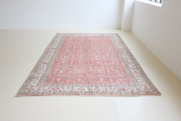 Ivy is a vintage rug handwoven in Turkey approximately 80 years ago. The warm red field and soft beige border are intertwined with an all over flowering vine pattern.