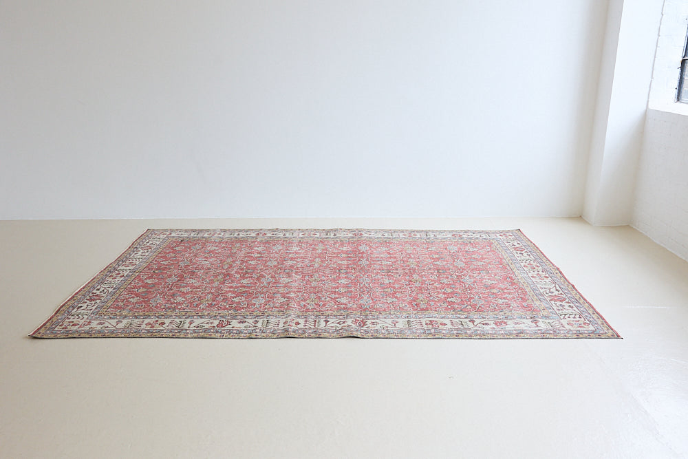Ivy is a vintage rug handwoven in Turkey approximately 80 years ago. The warm red field and soft beige border are intertwined with an all over flowering vine pattern.