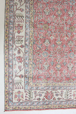 Ivy is a vintage rug handwoven in Turkey approximately 80 years ago. The warm red field and soft beige border are intertwined with an all over flowering vine pattern.