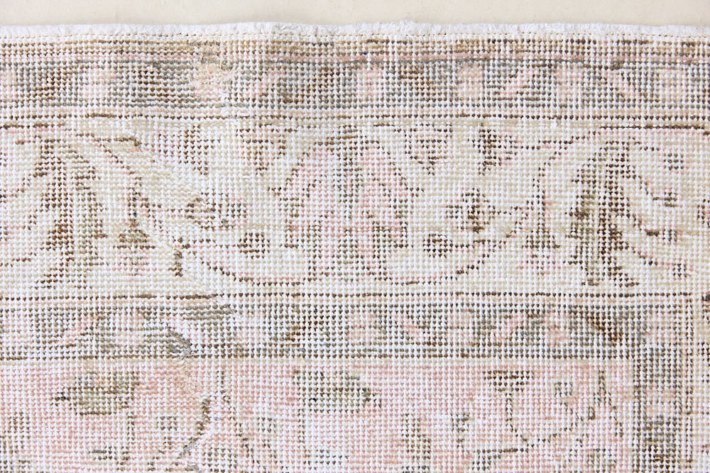 Lizzie is a vintage wool rug handwoven in Turkey approximately 70 years ago. The soft pink field and is decorated with an all floral scrolls pattern framed by a subtle contrasting taupe boarder.