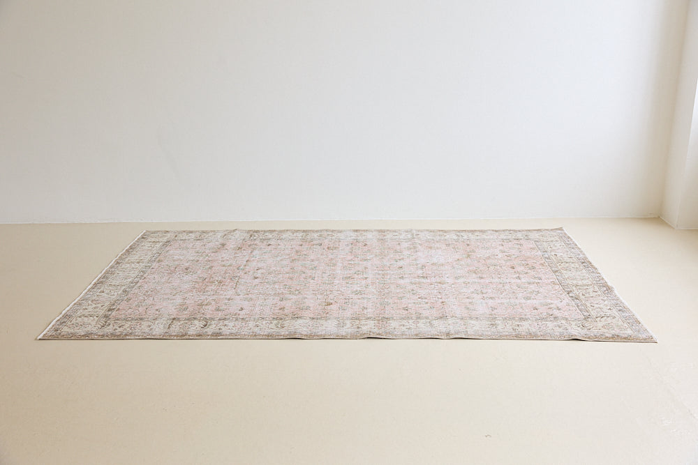 Lizzie is a vintage wool rug handwoven in Turkey approximately 70 years ago. The soft pink field and is decorated with an all floral scrolls pattern framed by a subtle contrasting taupe boarder.