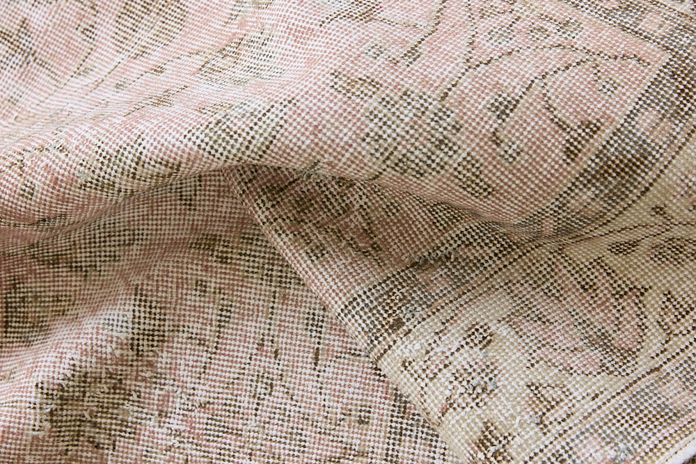 Lizzie is a vintage wool rug handwoven in Turkey approximately 70 years ago. The soft pink field and is decorated with an all floral scrolls pattern framed by a subtle contrasting taupe boarder.
