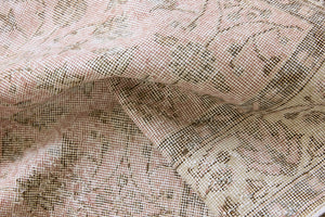 Lizzie is a vintage wool rug handwoven in Turkey approximately 70 years ago. The soft pink field and is decorated with an all floral scrolls pattern framed by a subtle contrasting taupe boarder.