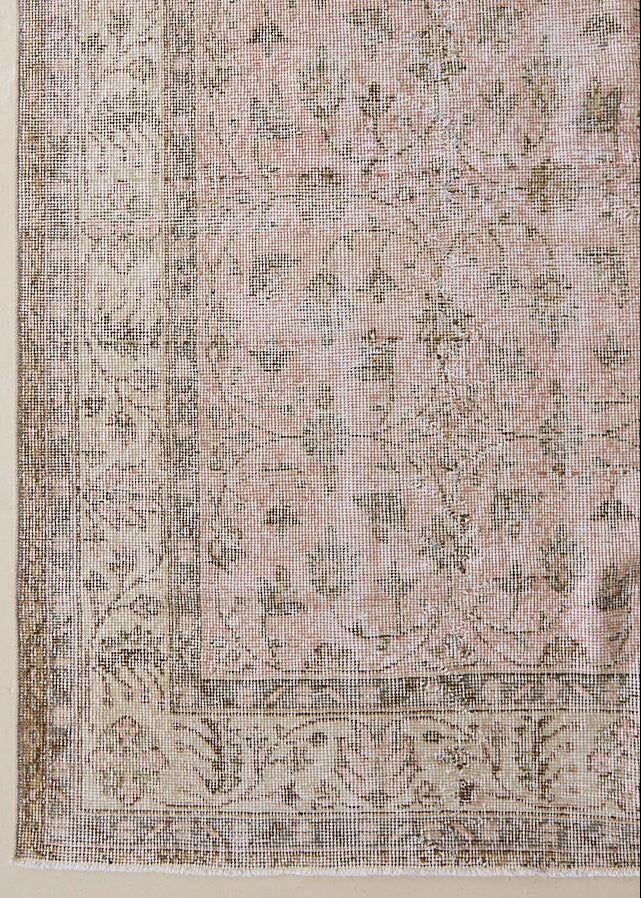 Lizzie is a vintage wool rug handwoven in Turkey approximately 70 years ago. The soft pink field of this Turkish carpet is decorated with an all floral scrolls pattern framed by a subtle contrasting taupe boarder.