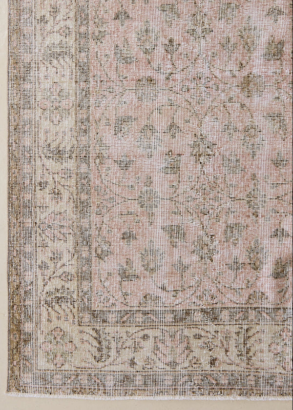 Lizzie is a vintage wool rug handwoven in Turkey approximately 70 years ago. The soft pink field of this Turkish carpet is decorated with an all floral scrolls pattern framed by a subtle contrasting taupe boarder.