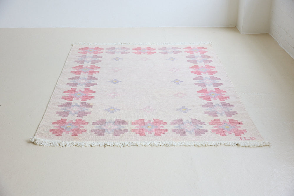 Ola is an original 1960s röllakan flatweave rug, featuring a pretty geometric floral pattern. The rug is signed ILS.