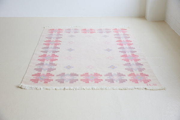 Ola is an original 1960s röllakan flatweave rug, featuring a pretty geometric floral pattern. The rug is signed ILS.