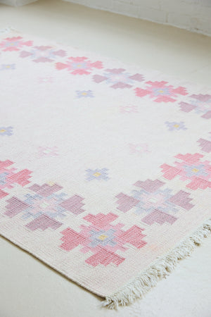 Ola is an original 1960s röllakan flatweave rug, featuring a pretty geometric floral pattern. The rug is signed ILS.