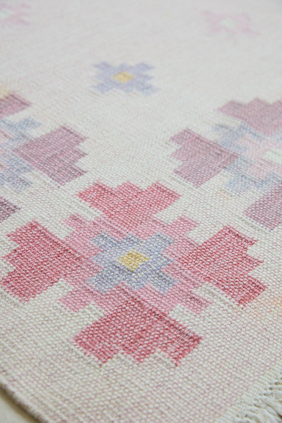 Ola is an original 1960s vintaage  rug. This röllakan flatweave features a pretty geometric floral pattern. The rug is signed ILS.