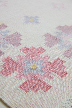 Ola is an original 1960s vintaage  rug. This röllakan flatweave features a pretty geometric floral pattern. The rug is signed ILS.