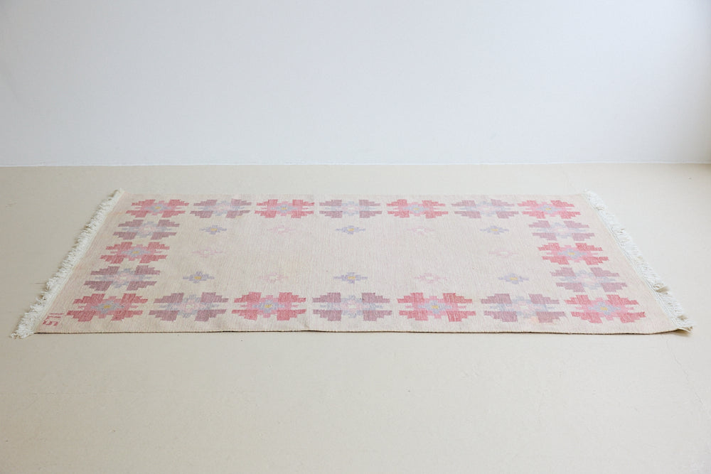 Ola is an original 1960s röllakan flatweave rug, featuring a pretty geometric floral pattern. The rug is signed ILS.