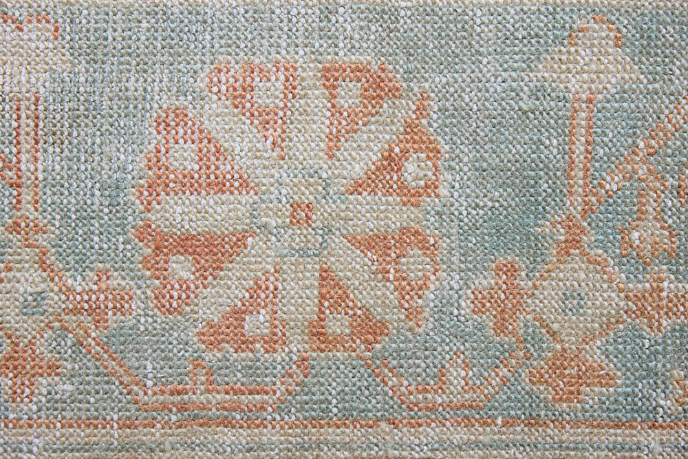 An antique Turkish Oushak rug. Perdita features a large-scale, open medallion pattern, flowing botanical motifs and a generous field space set against a blue and terracotta ground.