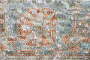 An antique Turkish Oushak rug. Perdita features a large-scale, open medallion pattern, flowing botanical motifs and a generous field space set against a blue and terracotta ground.