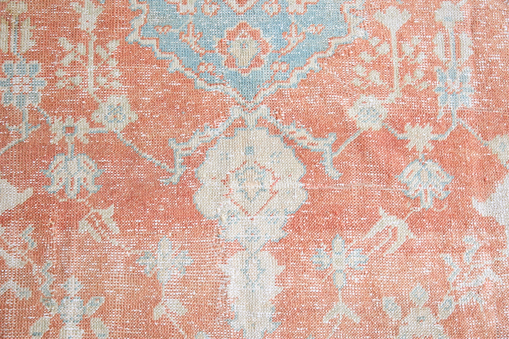 An antique Turkish Oushak rug. Perdita features a large-scale, open medallion pattern, flowing botanical motifs and a generous field space set against a blue and terracotta ground.