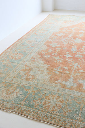An antique Turkish Oushak rug. Perdita features a large-scale, open medallion pattern, flowing botanical motifs and a generous field space set against a blue and terracotta ground.