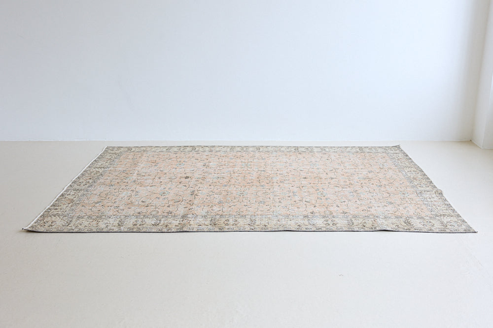 Rosh is a vintage wool rug handwoven in Turkey approximately 80 years ago. The soft terracotta field is decorated with an all floral scrolls pattern framed by a subtle contrasting taupe boarder.