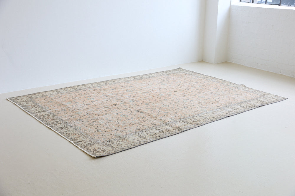 Rosh is a vintage wool rug handwoven in Turkey approximately 80 years ago. The soft terracotta field is decorated with an all floral scrolls pattern framed by a subtle contrasting taupe boarder.