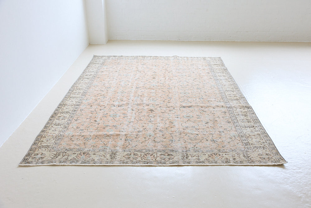 Rosh is a vintage wool rug handwoven in Turkey approximately 80 years ago. The soft terracotta field is decorated with an all floral scrolls pattern framed by a subtle contrasting taupe boarder.