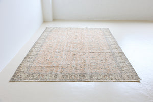 Rosh is a vintage wool rug handwoven in Turkey approximately 80 years ago. The soft terracotta field is decorated with an all floral scrolls pattern framed by a subtle contrasting taupe boarder.