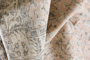 Rosh is a vintage wool rug handwoven in Turkey approximately 80 years ago. The soft terracotta field is decorated with an all floral scrolls pattern framed by a subtle contrasting taupe boarder.