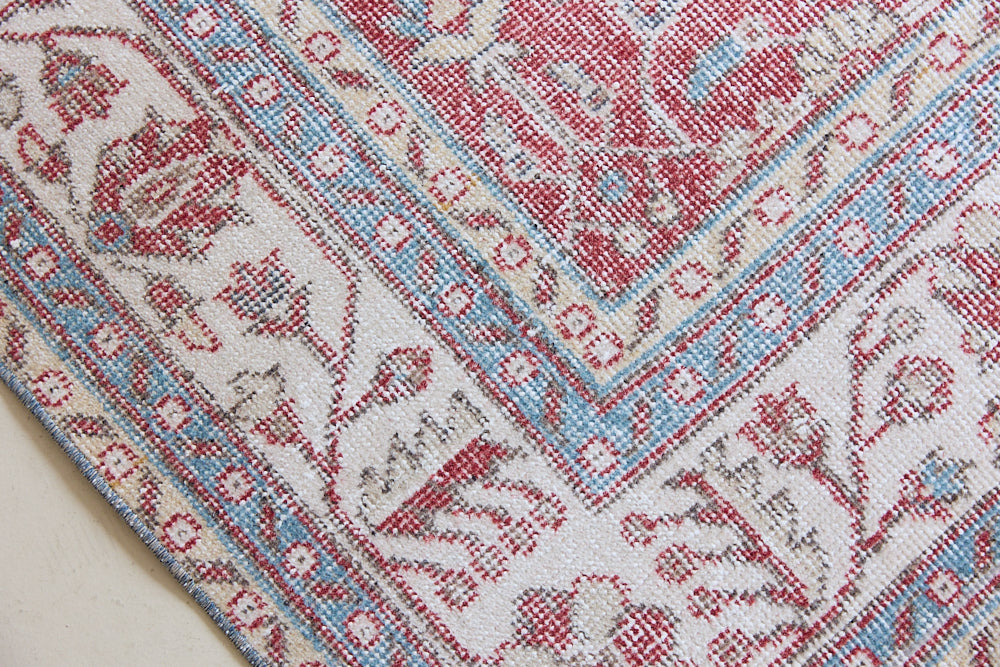 Teresa is a vintage rug handwoven in Turkey approximately 80 years ago. The warm red field and soft blue and beige border are intertwined with an all over flowering vine pattern.